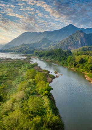 Flusslandschaft des Mekong in Laos mit Bergen im Hintergrund.
