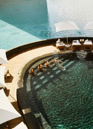 Aufsicht einer modernen Poollandschaft in einer exklusiven Hotelanlage mit Personen im Wasser.