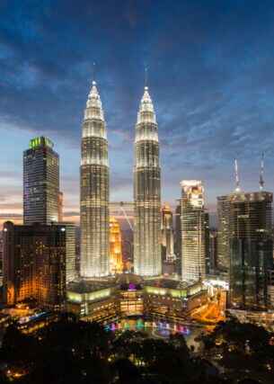Nachtaufnahme der erleuchteten Skyline der City von Kuala Lumpur mit den Petrona Twin Towers im Mittelpunkt.