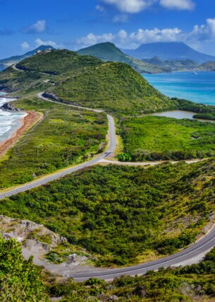 Aufnahme über die Landschaft und Küste der Insel St. Kitts mit der Insel Nevis im Hintergrund.