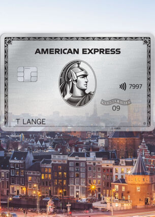 Fotocollage mit Freisteller einer silbernen Kreditkarte von American Express vor dem Stadtpanorama von Amsterdam in der Abenddämmerung.