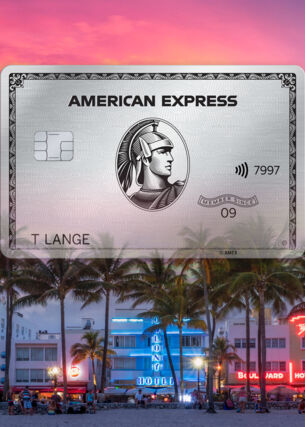 Freisteller einer Platinum Card von American Express vor der erleuchteten Oceanfront von Miami Beach hinter Palmen bei Sonnenuntergang.