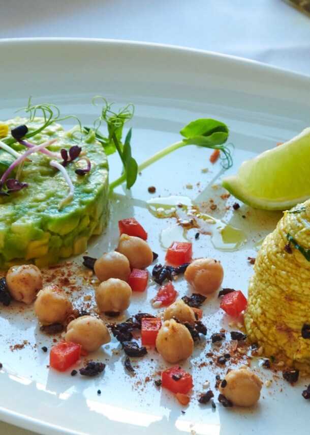 Ein weißer Porzellanteller mit einem Gericht aus Avocado, Kichererbsen, Limette und mehr im Restaurant brenner.