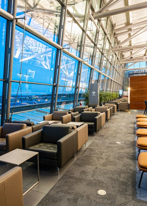 Eine Flughafenlounge mit Sitzgelegenheiten an Panoramafenstern.