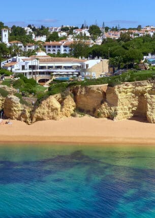 Luftaufnahme der Hotelanlage des Vila Vita Parc, das direkt an einer Klippe liegt. Darunter befindet sich ein Sandstrand und türkisblaues Meer.