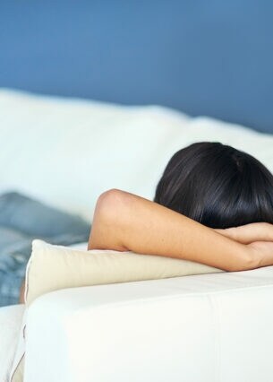 Rearview shot of a young woman lying on the sofa at home