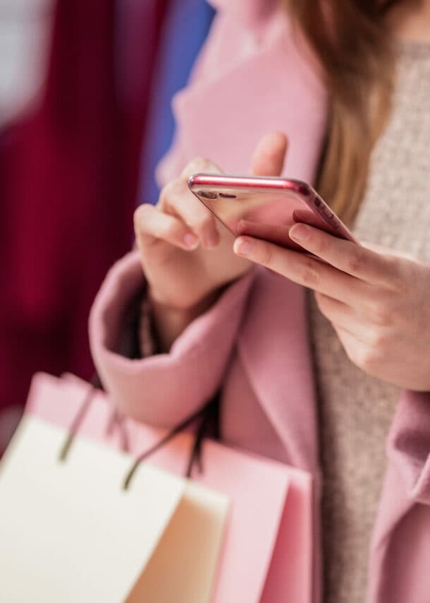 Eine Frau tippt beim Shopping auf ihrem Smartphone.