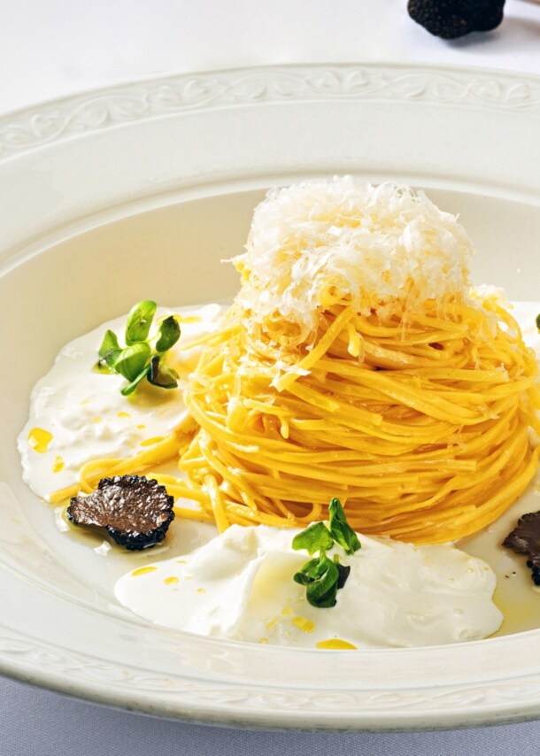 Spaghetti-Gericht mit Burrata und Trüffel, edel angerichtet auf einem weißen Teller.
