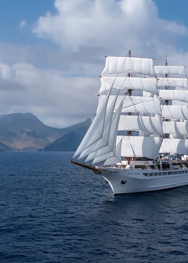 Großes Segelschiff auf dem Meer, im Hintergrund Berge