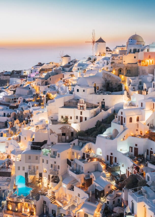 Dorf in Hanglage an einer Feldsküste mit beleuchteten weißen Häusern bei Sonnenuntergang.