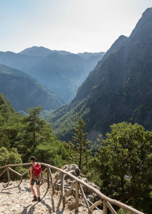 Eine Person beim Wandern in der Samaria-Schlucht auf Kreta, im Hintergrund Vegetation und Berggipfel.