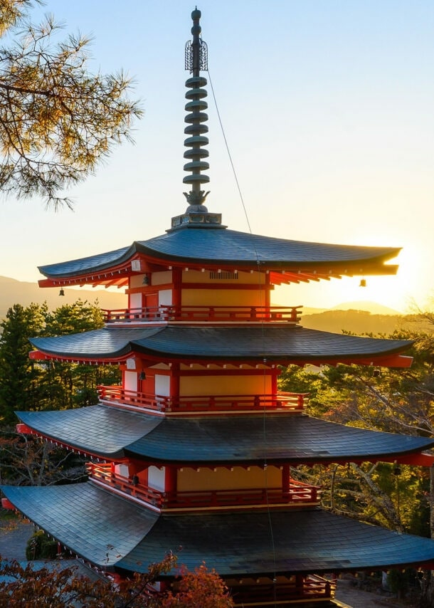 Ein Tempel im Pagodenstil auf einer bewaldeten Anhöhe über einer Stadt, im Hintergrund ein Berg mit Schneekuppe.