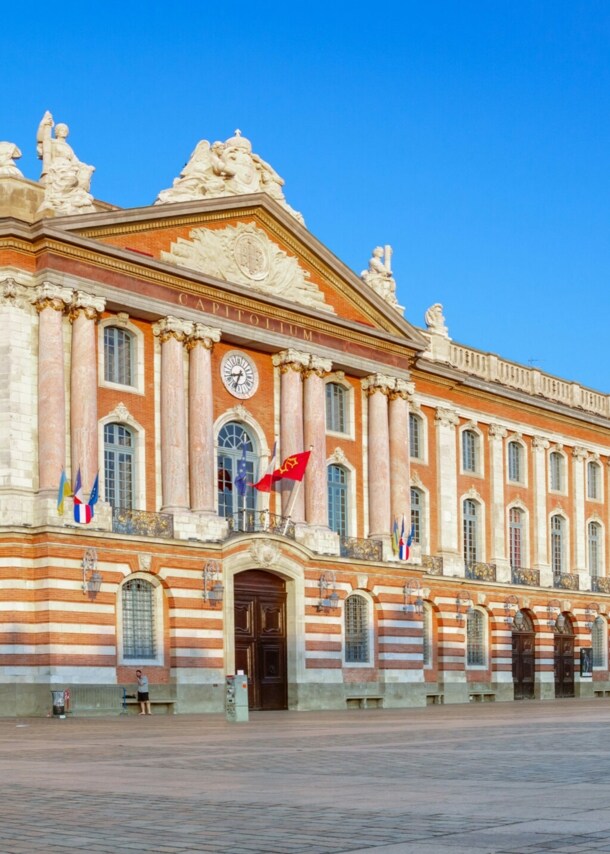 Ein Rathaus mit neoklassizistischer Fassade an einem Platz im Stadtkern.