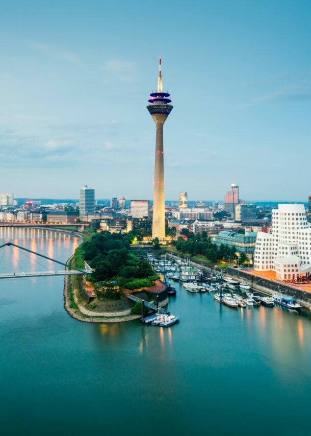 Skyline von Düsseldorf mit Fernsehturm am Hafen mit modernen Gebäuden in der Abenddämmerung.