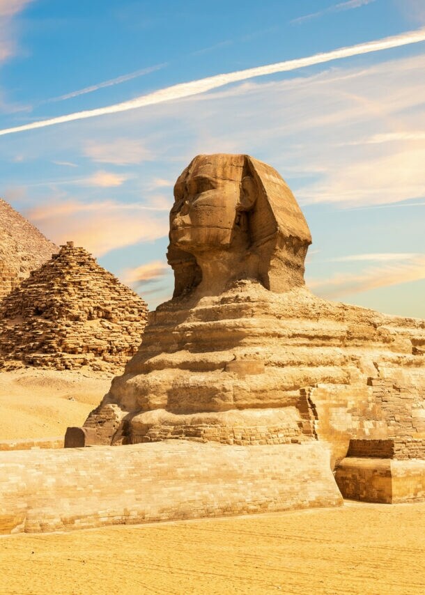 Sphinx Statue neben den Pyramiden von Gizeh in Wüstenlandschaft, im Vordergrund eine silberne Kreditkarte von American Express als Freisteller.