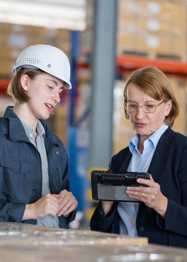 Zwei Frauen einer unterschiedlichen Generationen stehen zusammen in einem Lagerraum.