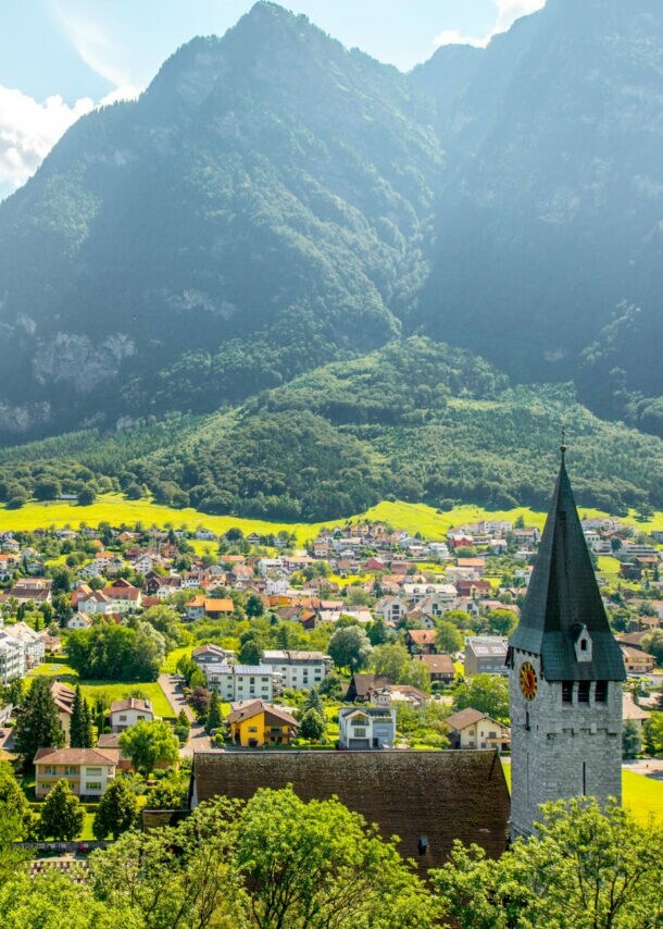 Landschaftsaufnahme eines Tals in Liechtenstein mit Kirche, vielen Häusern und Bergpanorama