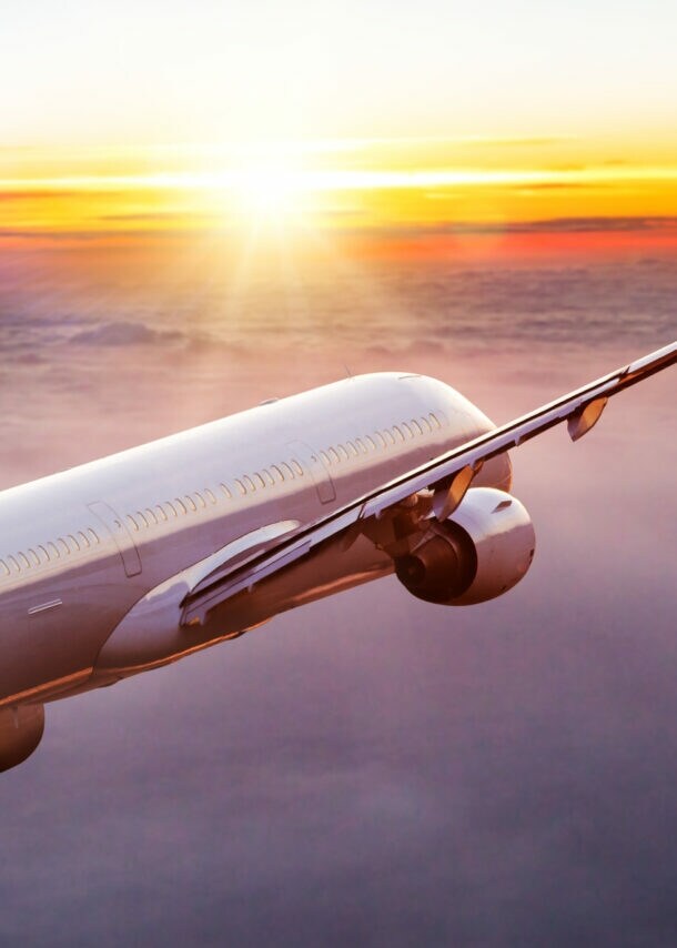 Ein geneigtes Passagierflugzeug über den Wolken bei Sonnenuntergang.