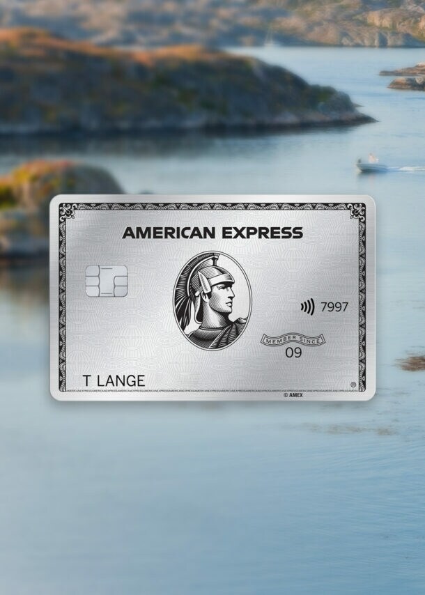 Schärenlandschaft mit Personen im Wasser vor einem roten Holzhaus im schwedischen Stil auf einem Felsen, im Vordergrund eine silberne Kreditkarte von American Express als Freisteller.