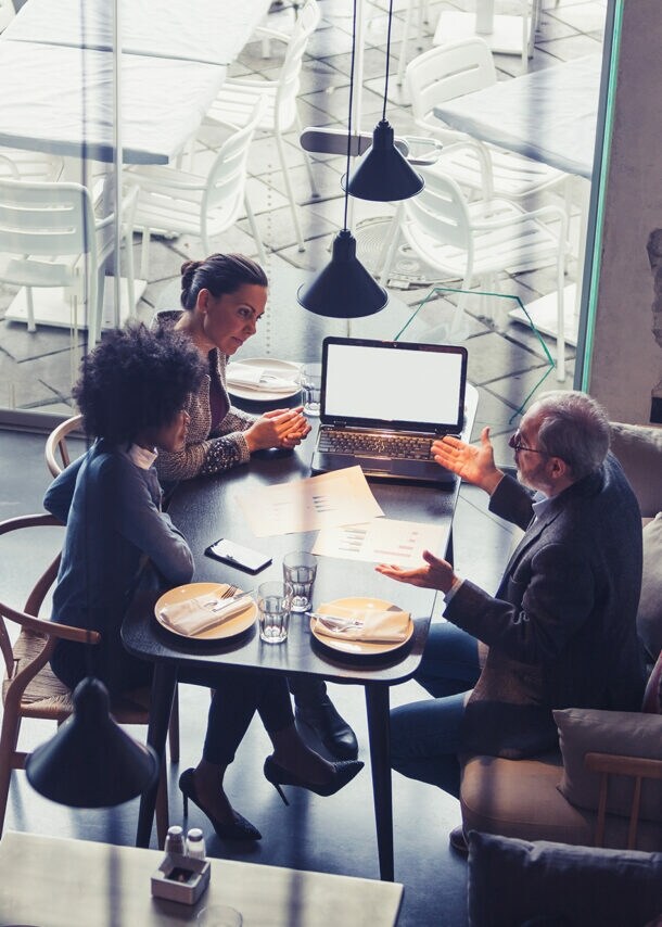 Mehrere Personen sitzen in einem Café für ein Arbeitsmeeting.