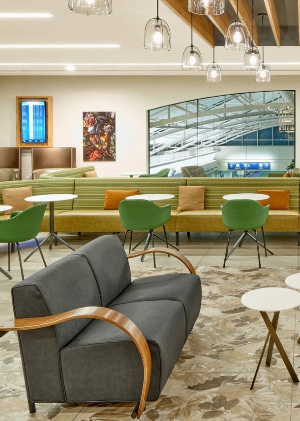 Moderne, elegante Flughafen-Lounge mit unterschiedlichen Sitzgelegenheiten und einem Panoramafenster mit Blick in den Terminal.