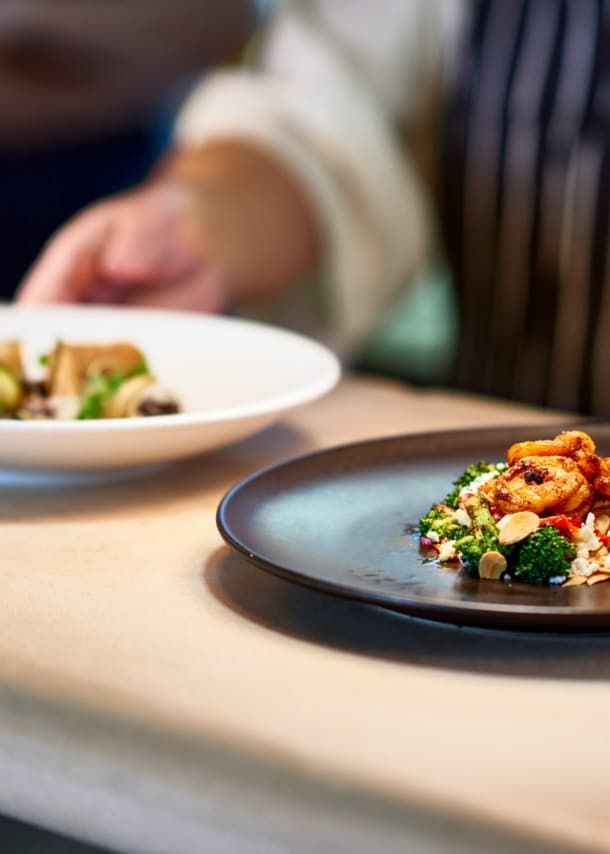 Ein Koch stellt zwei Teller mit zubereiteten Speisen auf die Theke.