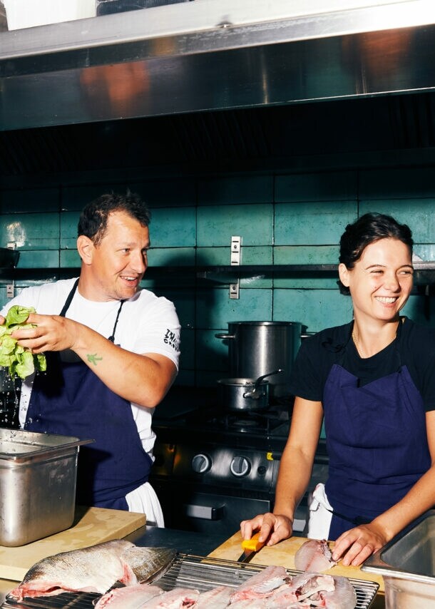 Koch und Köchin bereiten Salat und Fisch in der Restaurantküche vor.