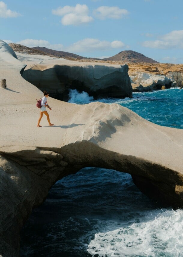 Eine Frau läuft auf einer bizarren Felsformation aus Vulkangestein am Meer.