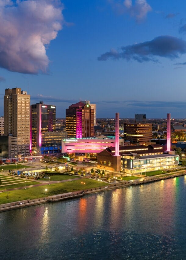 Stadtansicht von Toledo bei Abenddämmerung mit beleuchteten Gebäuden und reflektierendem Wasser im Vordergrund