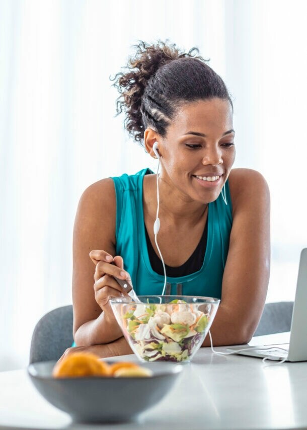 Eine Frau isst einen Salat an ihrem Arbeitsplatz.