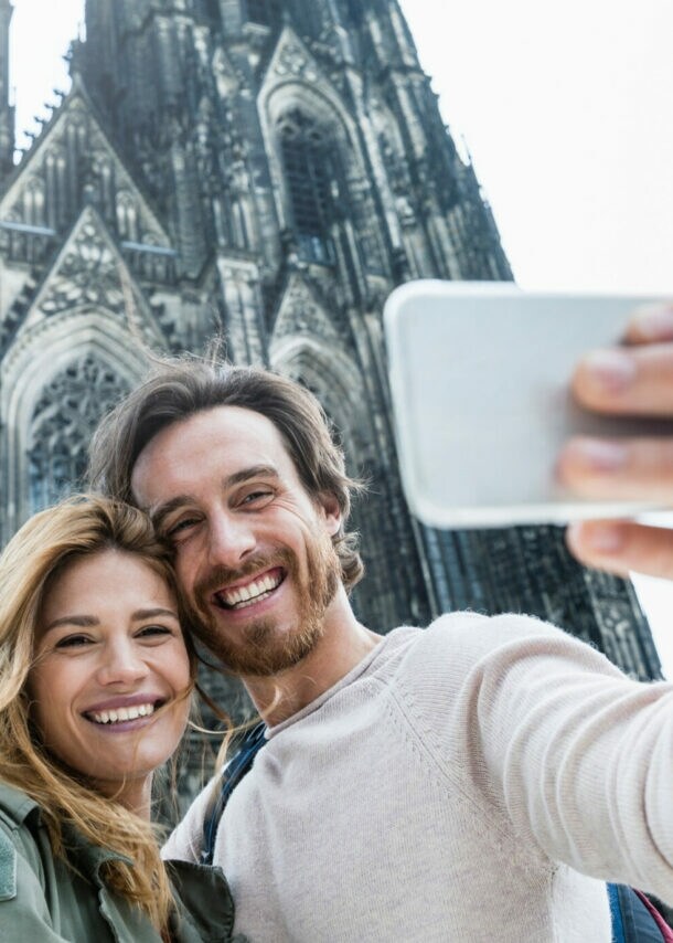 Junges Paar macht Selfie vor dem gotischen Kölner Dom an einem hellen Tag