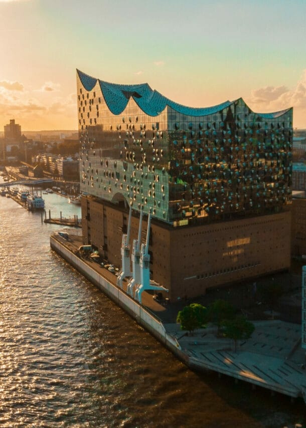 Sonnenuntergang über der Elbphilharmonie in Hamburg mit einem Schiff auf der Elbe und Stadtansicht im Hintergrund.
