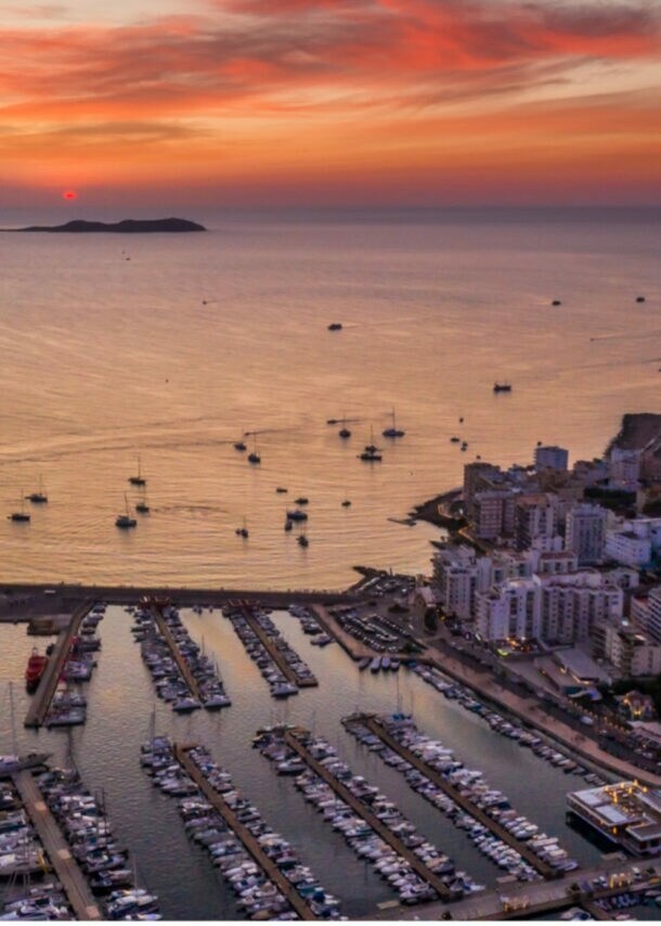 Luftaufnahme eines Hafens mit vielen Booten und Yachten bei Sonnenuntergang mit orangefarbenem Himmel