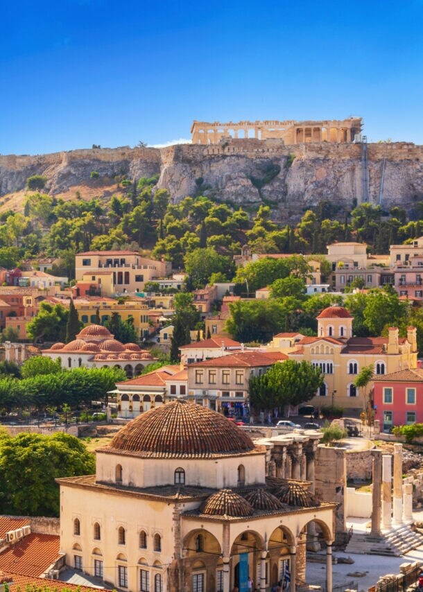 Blick auf die Akropolis von Athen mit blühendem Bougainvillea im Vordergrund und historischen Gebäuden darunter