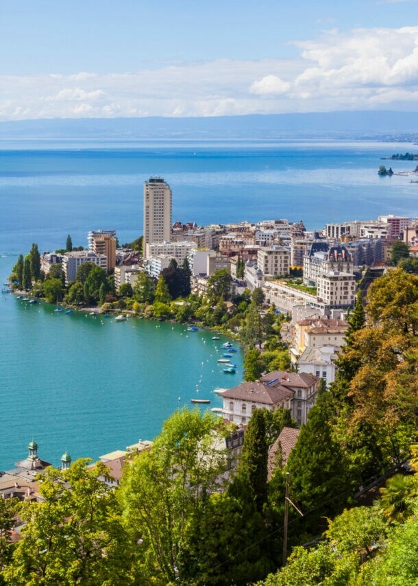 Blick auf den Genfersee mit einem Ausflugsboot, umgeben von Bergen und der Stadt Montreux am Ufer