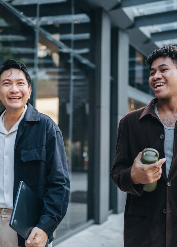 Zwei Kollegen spazieren gemeinsam und halten dabei eine Projektbesprechung ab.