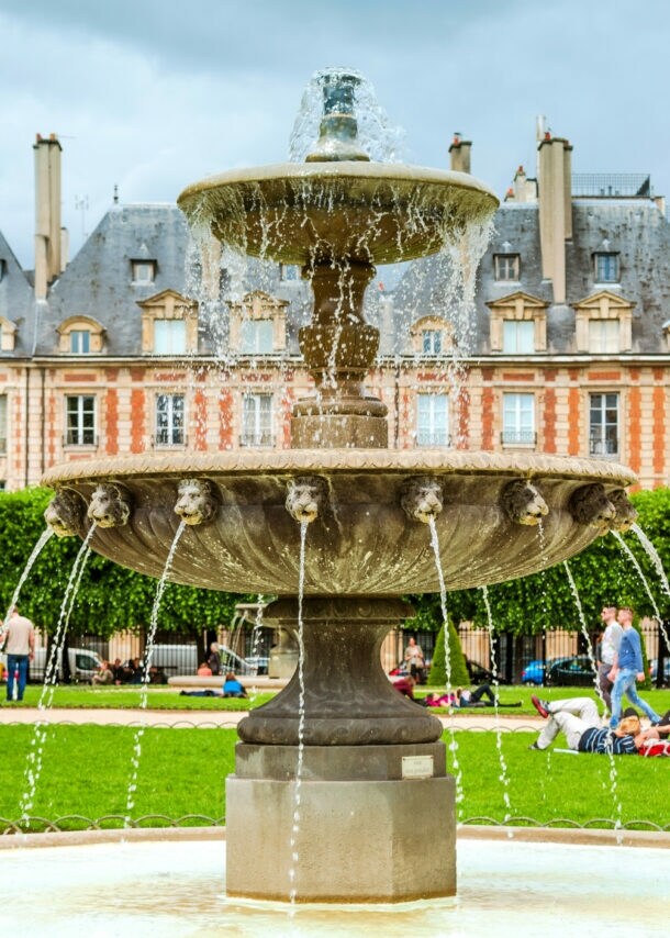 Brunnen mit fließendem Wasser im Place des Vosges, Paris, vor historischen Gebäuden und Bäumen