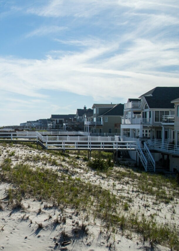 Weg zu einem Sandstrand mit Dünen unter blauem Himmel.