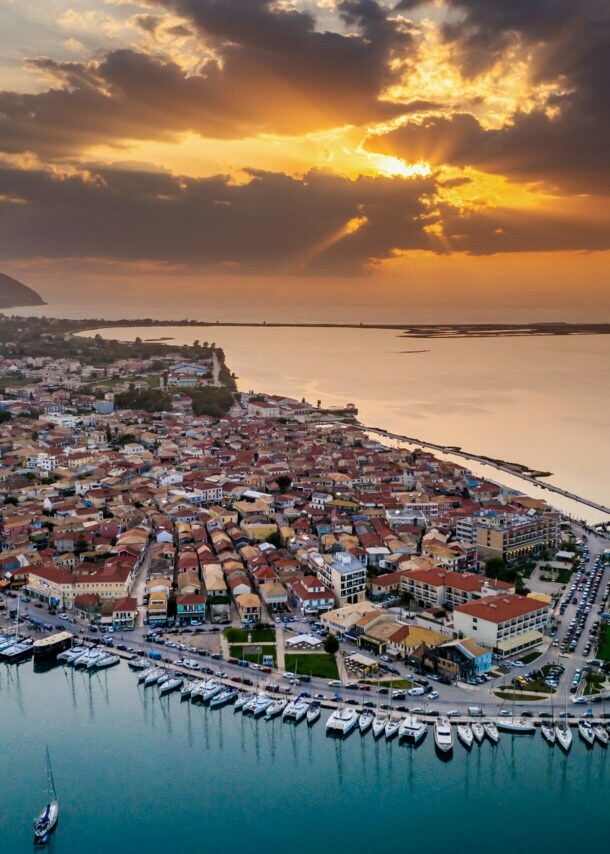 Küstenort mit Hafen von oben bei Sonnenuntergang umgeben von Meer.