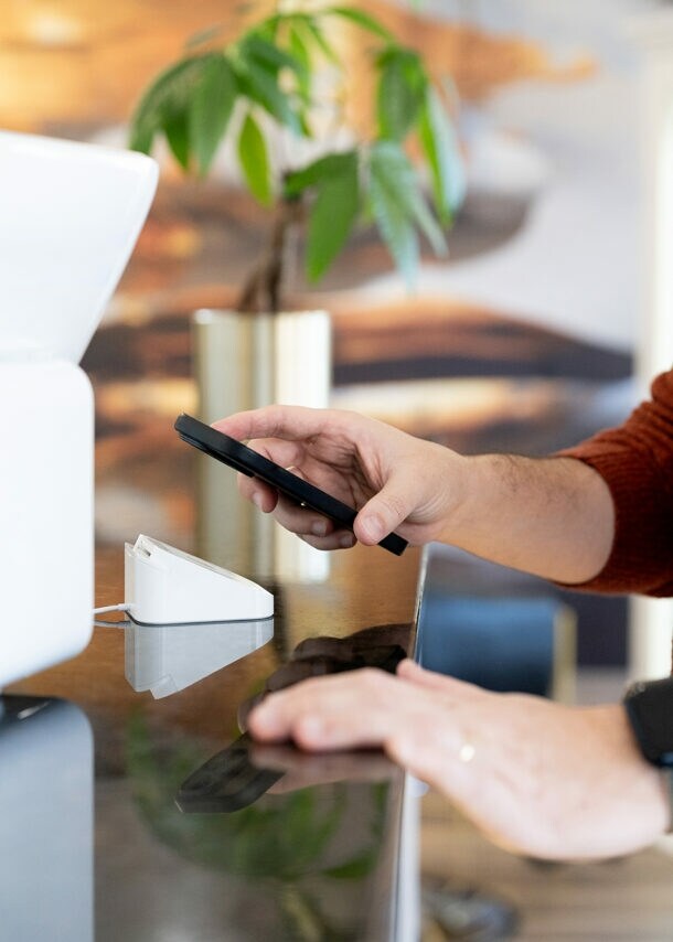 Nahaufnahme eines Mannes, der via Smartphone eine Zahlung in einem Geschäft tätigt.