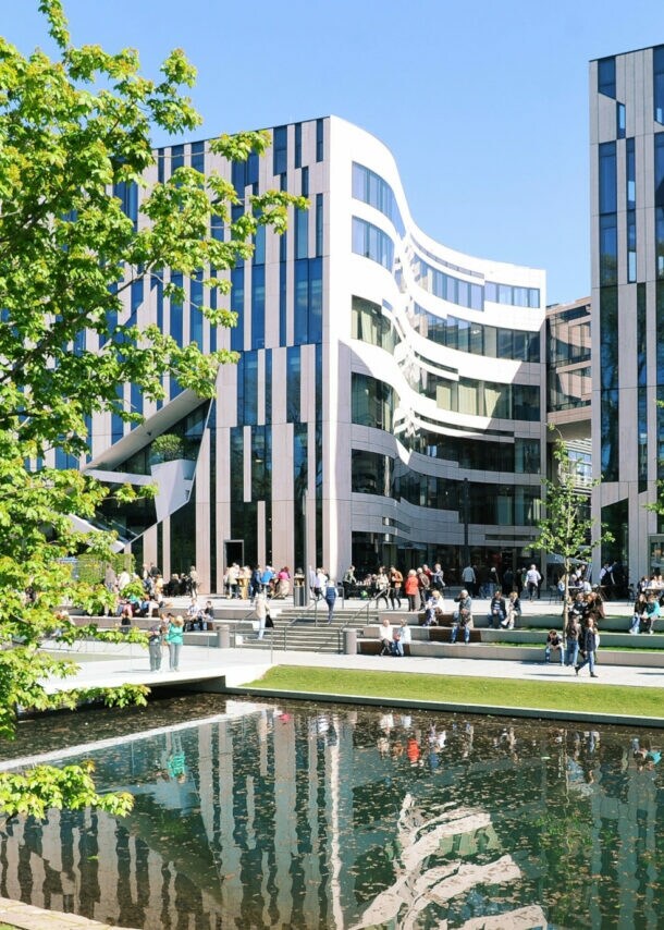 Moderne Bürogebäude mit Glasfassaden am Wasserbecken im Kö-Bogen Düsseldorf, Menschen sitzen und gehen auf der Promenade