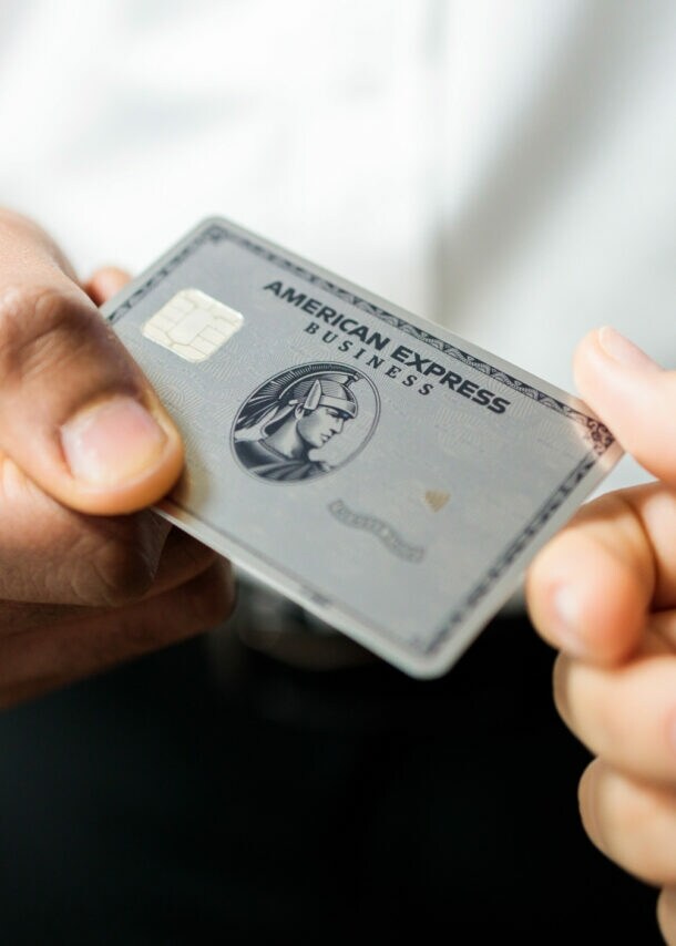 Eine Person übergibt einer anderen eine Business Platinum Card von American Express.