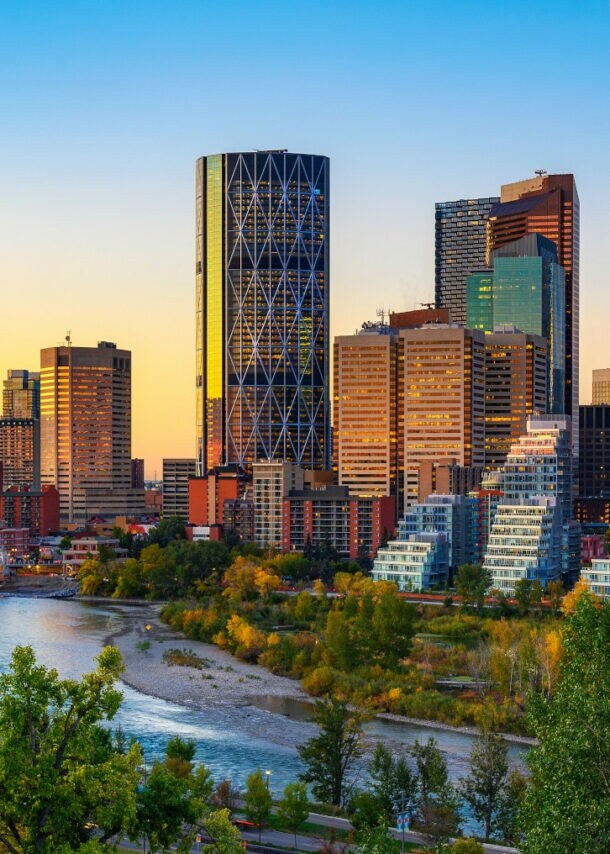 Sonnenuntergang über der Skyline der kanadischen Stadt Calgary, mit dem Bow River im Vordergrund.