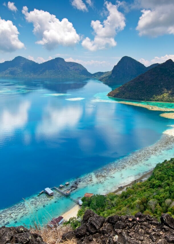 Panorama mehrerer Inseln mit bewaldeten Hügeln und Lagune im türkisblauen Meer.