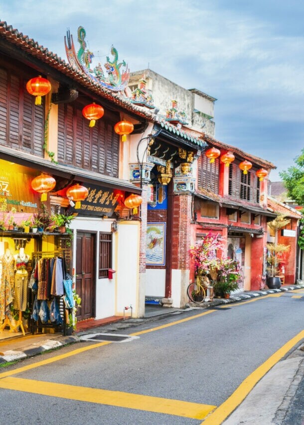 Schmale Straße mit Geschäften und roten Lampions um den Eingang zu einem chinesischen Tempel.