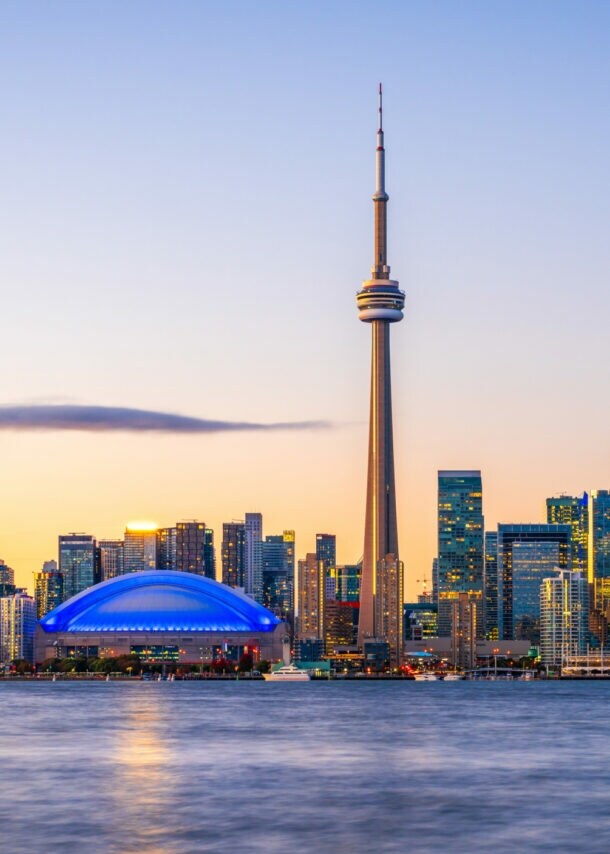 Skyline von Toronto mit Hochhäusern und Fernsehturm am Wasser im Abendlicht.