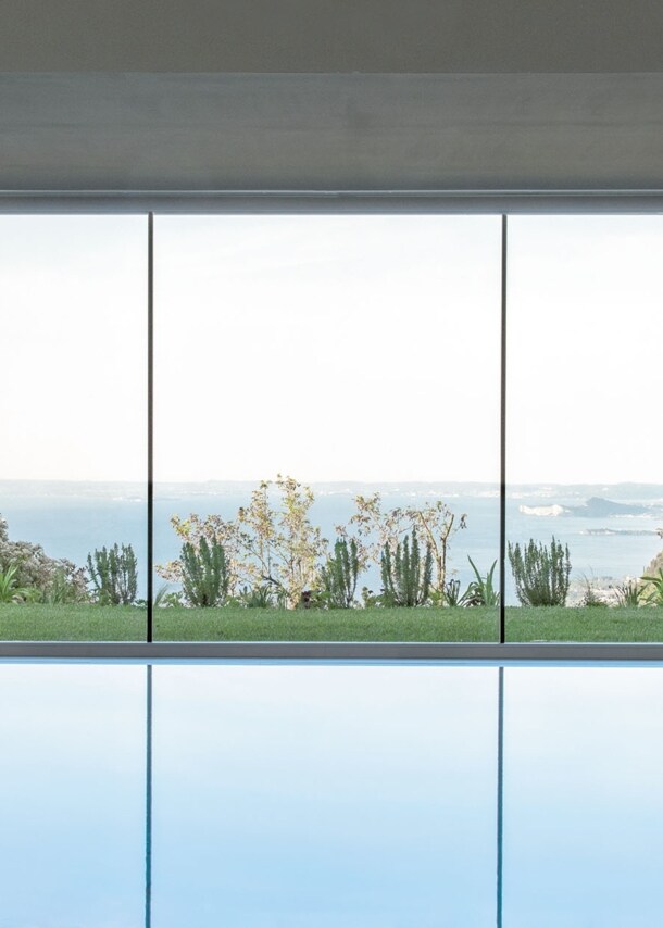 Indoor-Pool vor Panoramafenster mit Seeblick.