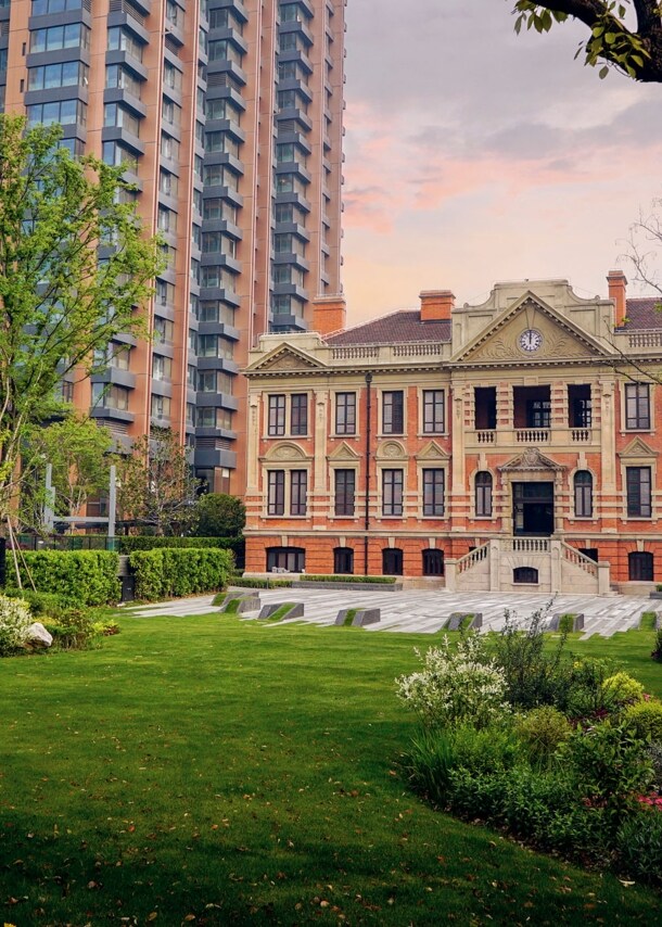Hotelanlage mit historischem Gebäude neben einem Hochhaus in einer Gartenanlage.