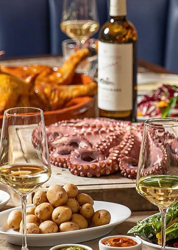 Restauranttisch mit Tapasgerichten und Tintenfisch mit Weingläsern.