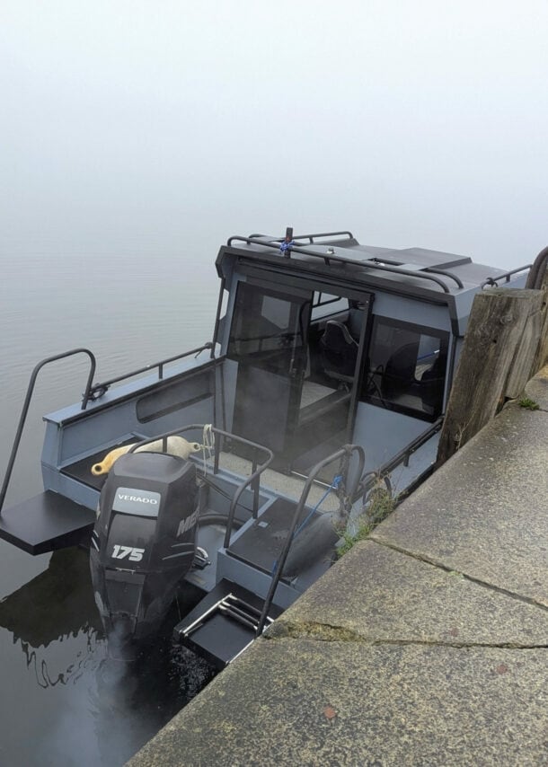 Ein Motorboot liegt bei dichtem Nebel an einer Kaimauer.